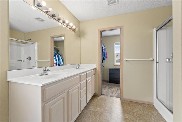 bathroom with a stall shower, a spacious closet, visible vents, and a sink