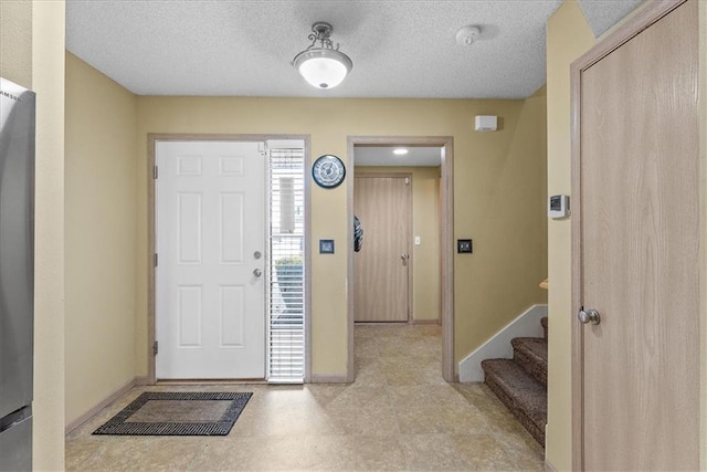 entrance foyer with a textured ceiling, stairway, and baseboards