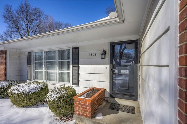 snow covered property entrance with brick siding