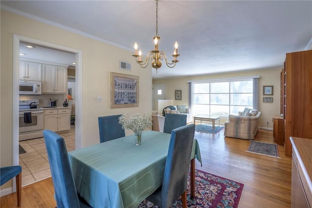 dining room with visible vents, ornamental molding, a chandelier, light wood-type flooring, and baseboards