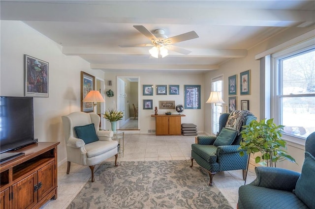 living area with light tile patterned flooring, beamed ceiling, baseboards, and ceiling fan