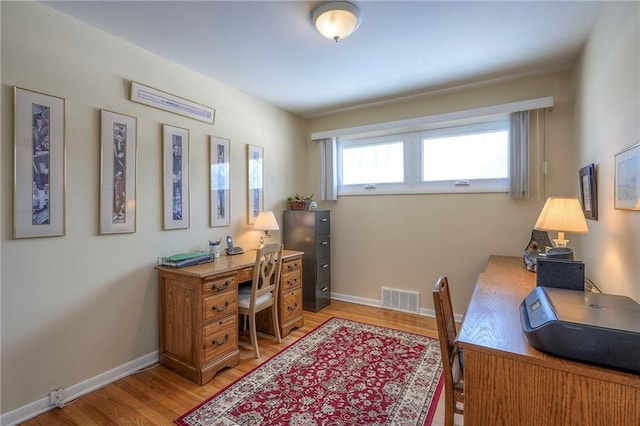 home office with light wood-style floors, visible vents, and baseboards