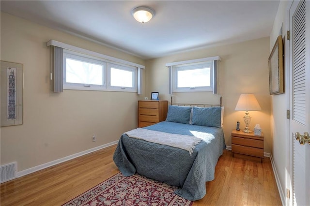 bedroom with baseboards, visible vents, and light wood finished floors