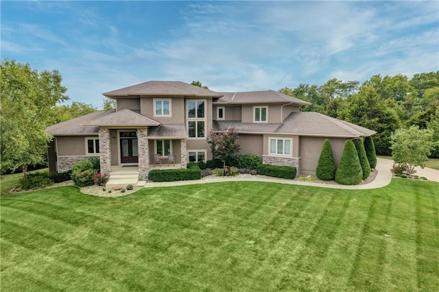 prairie-style house featuring stone siding, a front yard, and stucco siding