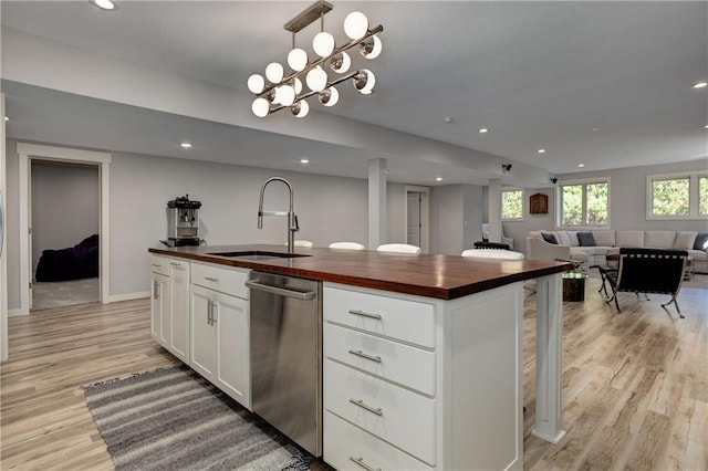 kitchen with butcher block counters, a sink, white cabinets, open floor plan, and light wood finished floors