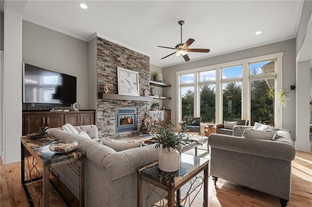 living room with a stone fireplace, ornamental molding, light wood-type flooring, and recessed lighting