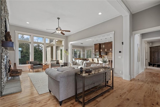 living room with crown molding, a stone fireplace, and light wood-style floors