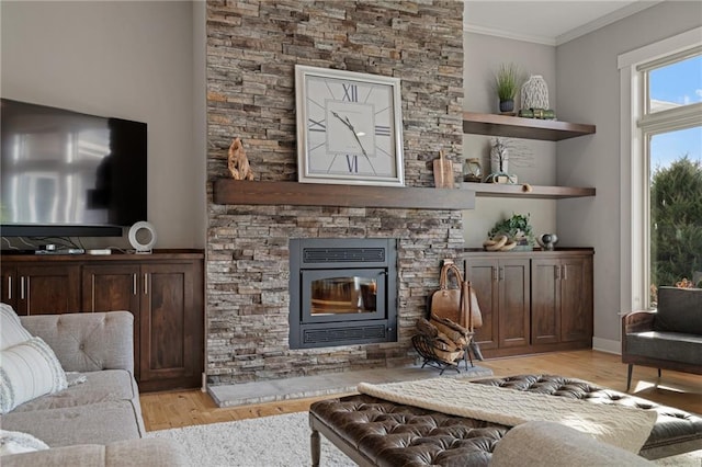 living area featuring light wood finished floors, ornamental molding, and a stone fireplace