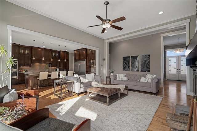 living room featuring a ceiling fan, light wood-type flooring, crown molding, and recessed lighting