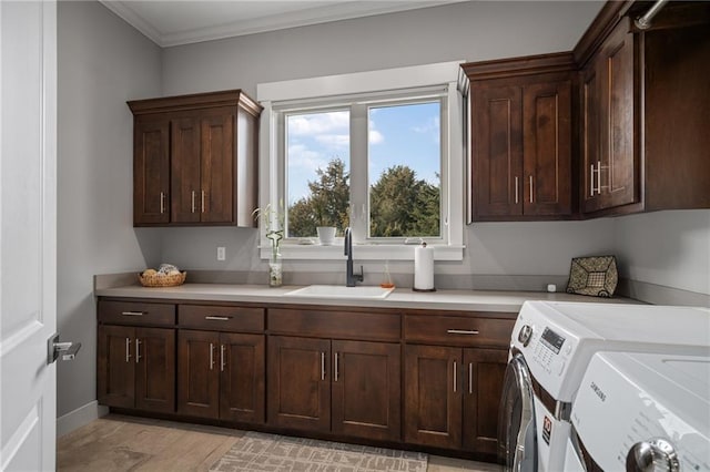 laundry room featuring separate washer and dryer, a sink, baseboards, cabinet space, and crown molding