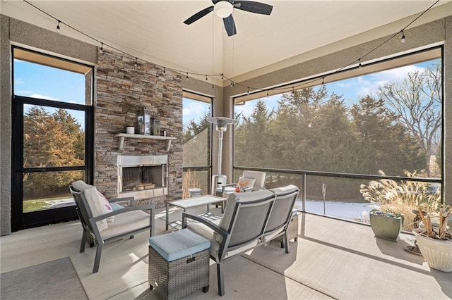 sunroom / solarium with an outdoor stone fireplace and a ceiling fan