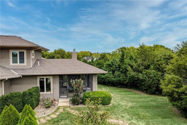 exterior space with stucco siding, a shingled roof, a chimney, and a front yard