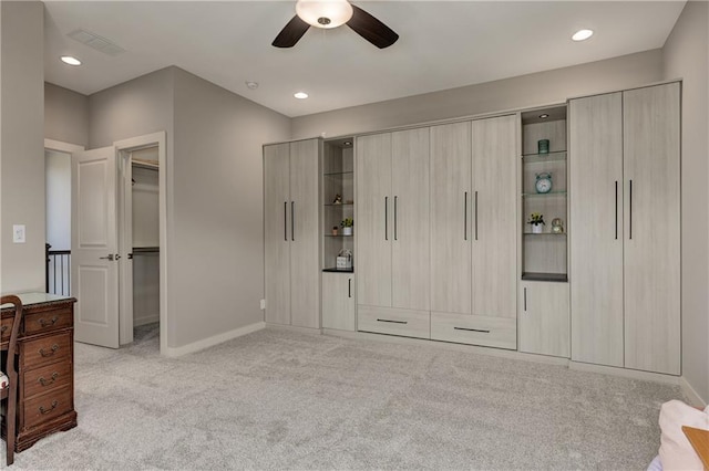 bedroom featuring recessed lighting, light colored carpet, a ceiling fan, baseboards, and a walk in closet