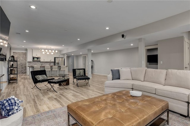 living room featuring light wood-style floors, baseboards, an inviting chandelier, and recessed lighting