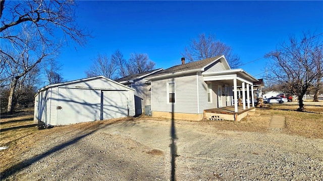 view of side of property with a garage, an outdoor structure, and covered porch