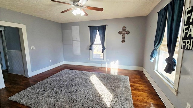 unfurnished room featuring ceiling fan, dark wood-type flooring, and a textured ceiling