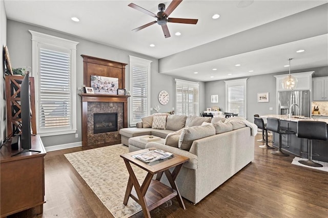 living room featuring ceiling fan, dark hardwood / wood-style floors, sink, and a fireplace