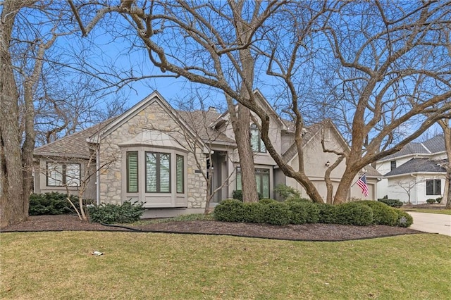 view of front facade with stone siding, a front lawn, driveway, and stucco siding