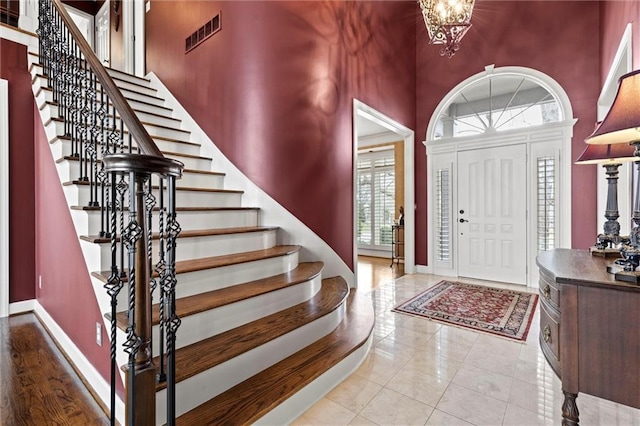 foyer featuring baseboards, a high ceiling, visible vents, and a chandelier