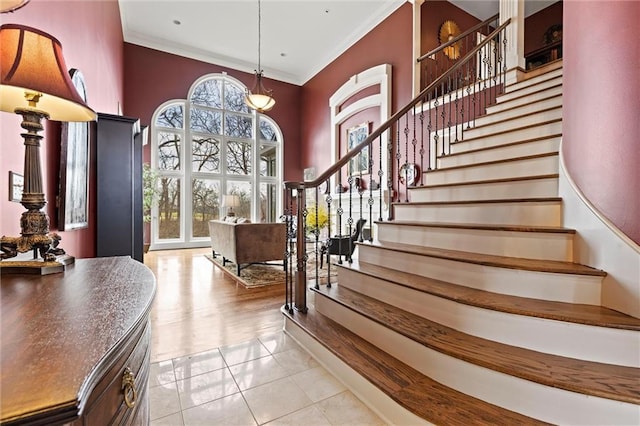 entryway with light tile patterned floors, stairs, and ornamental molding