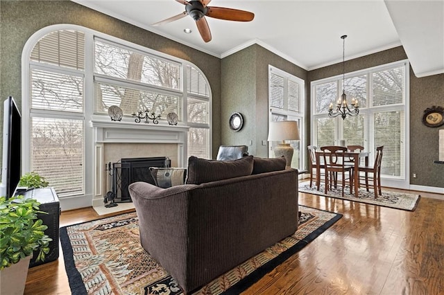 living area featuring a fireplace, plenty of natural light, wood finished floors, and crown molding