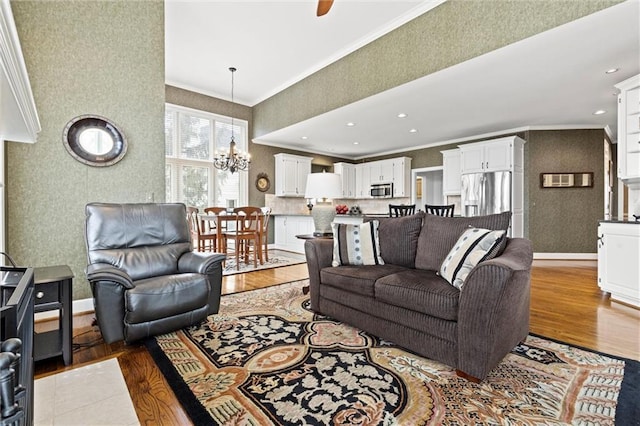 living room with crown molding, a notable chandelier, recessed lighting, wood finished floors, and baseboards