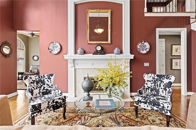 sitting room featuring ceiling fan, a fireplace, baseboards, and wood finished floors