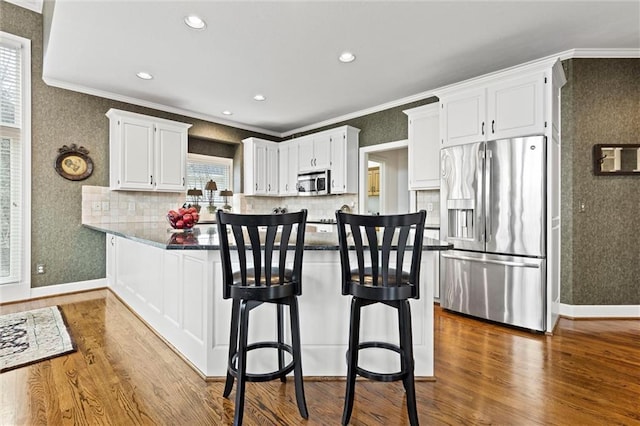 kitchen featuring a peninsula, dark wood-style flooring, white cabinetry, appliances with stainless steel finishes, and wallpapered walls