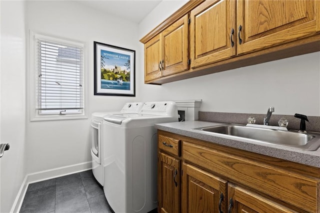 laundry room with cabinet space, a sink, independent washer and dryer, dark tile patterned floors, and baseboards