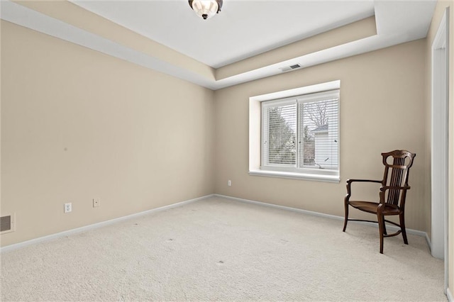 unfurnished room with baseboards, a tray ceiling, visible vents, and light colored carpet