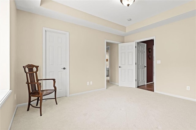 sitting room with carpet floors, a tray ceiling, and baseboards