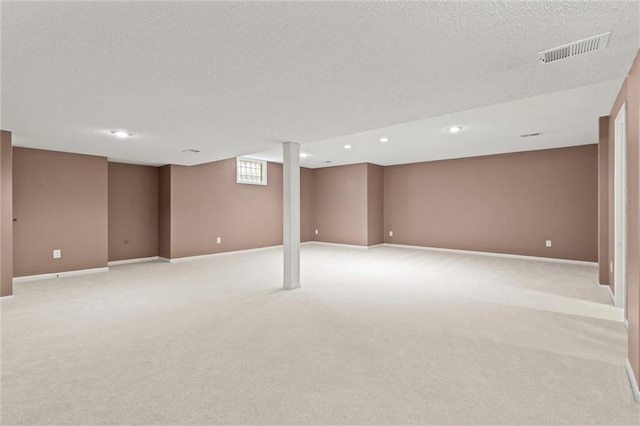 below grade area with visible vents, a textured ceiling, and baseboards