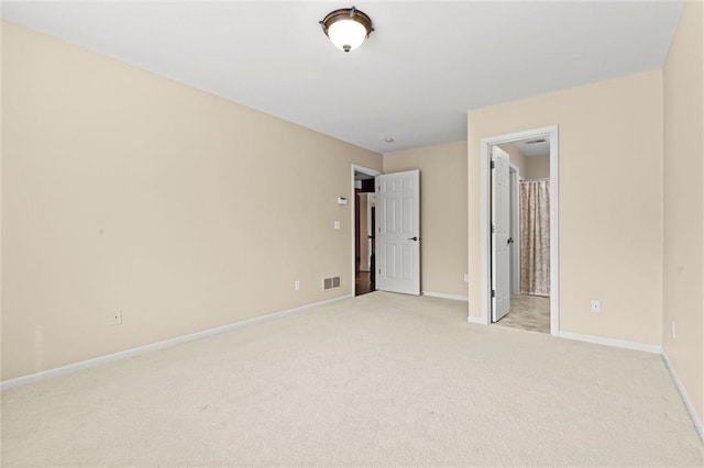 empty room featuring light carpet, visible vents, and baseboards