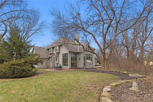 view of front of property with stucco siding, a chimney, a front lawn, and a patio