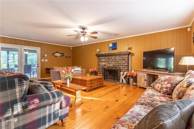 living room featuring crown molding, ceiling fan, a fireplace, and hardwood / wood-style flooring