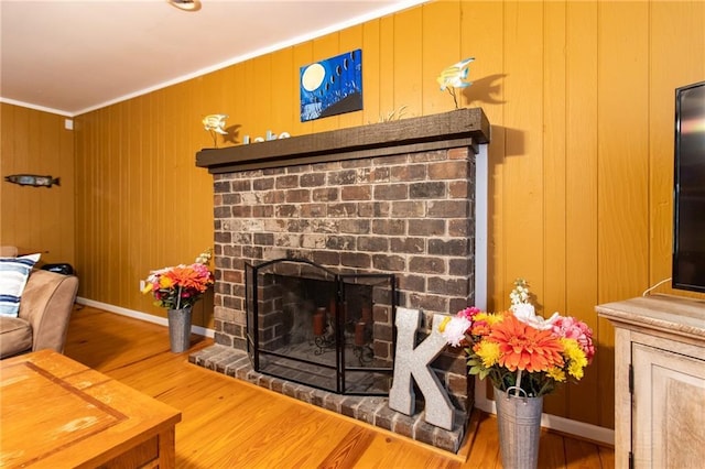 room details featuring crown molding, wood-type flooring, wooden walls, and a brick fireplace