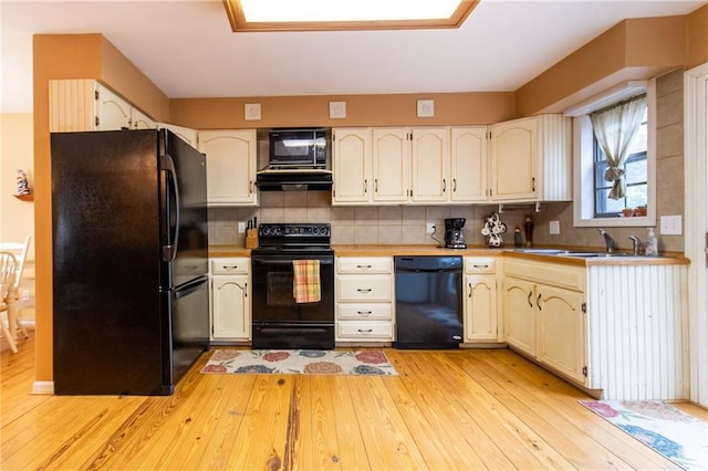 kitchen featuring tasteful backsplash, sink, black appliances, and light wood-type flooring