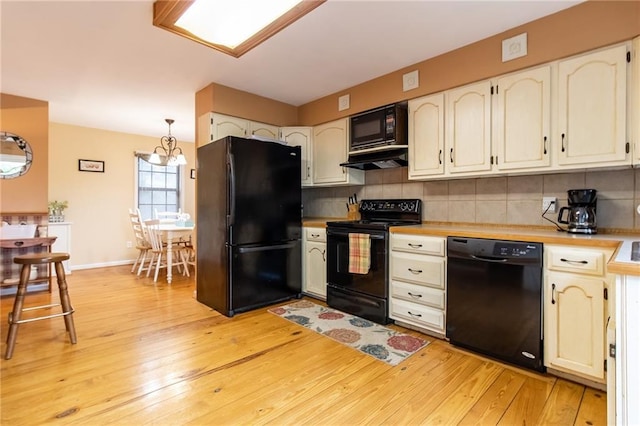 kitchen with tasteful backsplash, white cabinets, light wood-type flooring, and black appliances