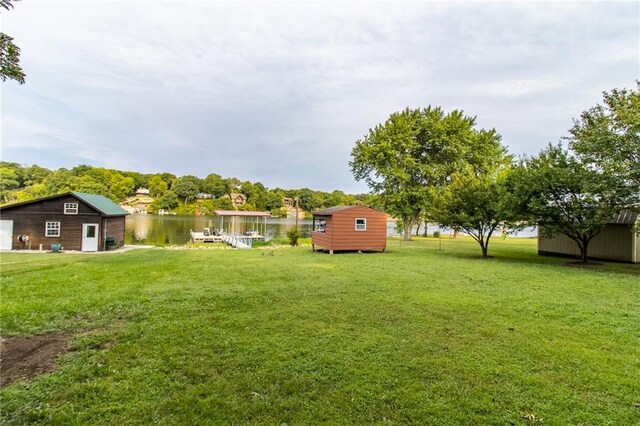 view of yard with a storage shed, a boat dock, and a water view