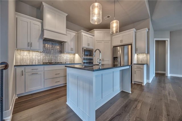 kitchen featuring white cabinetry, stainless steel appliances, and an island with sink