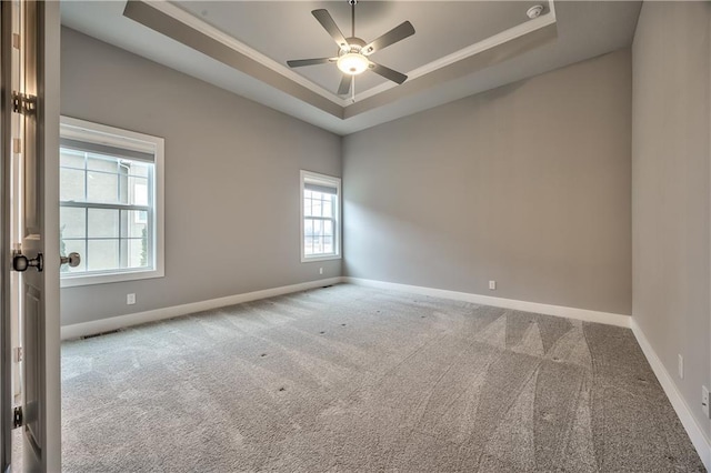 carpeted spare room with ceiling fan and a tray ceiling