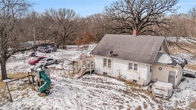 snow covered rear of property with a playground