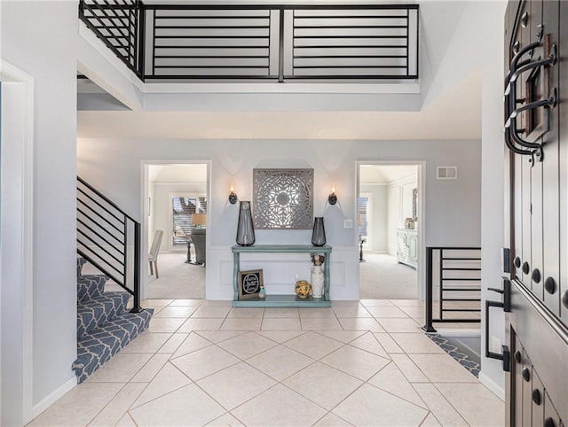 foyer entrance featuring light tile patterned floors, visible vents, and light colored carpet