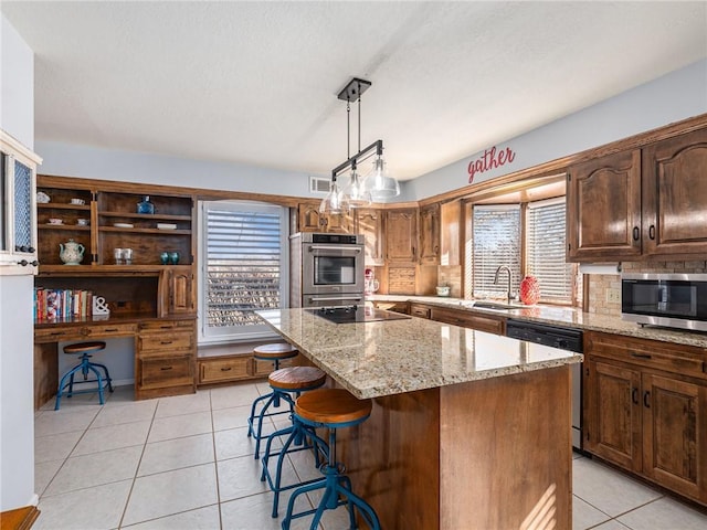 kitchen with light tile patterned floors, a sink, visible vents, appliances with stainless steel finishes, and a center island