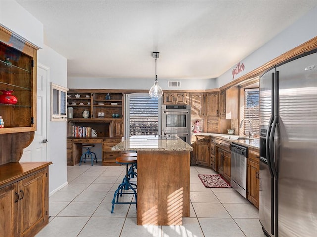 kitchen with light tile patterned floors, stainless steel appliances, visible vents, a sink, and a kitchen breakfast bar