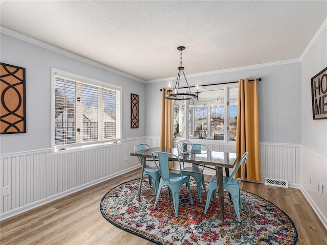 dining space featuring a wainscoted wall, wood finished floors, and visible vents