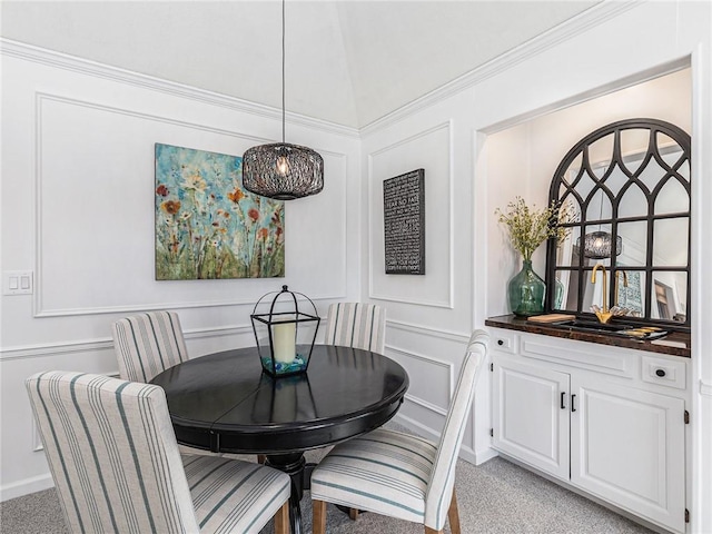 dining space with light carpet, vaulted ceiling, and a decorative wall