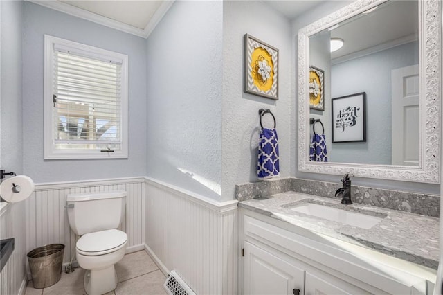 half bath featuring a wainscoted wall, toilet, ornamental molding, vanity, and tile patterned floors