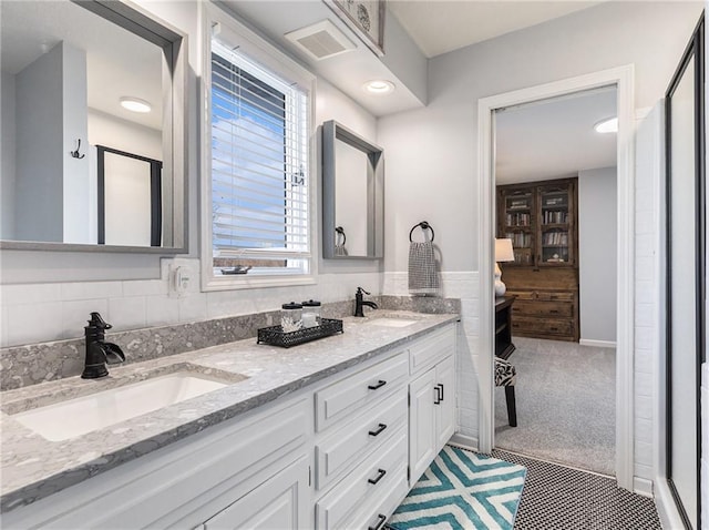 bathroom featuring double vanity, a stall shower, a sink, and visible vents