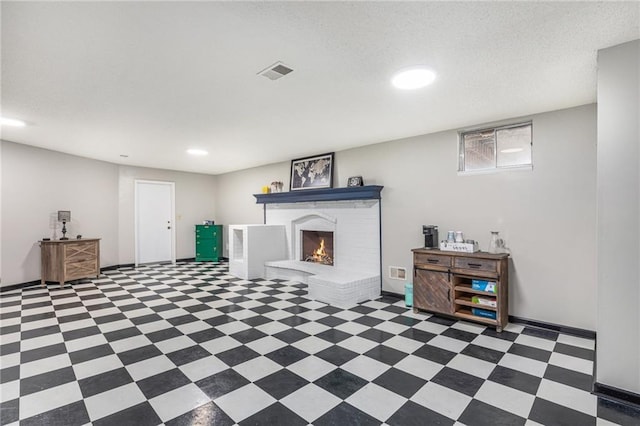 below grade area featuring a fireplace, visible vents, a textured ceiling, baseboards, and tile patterned floors